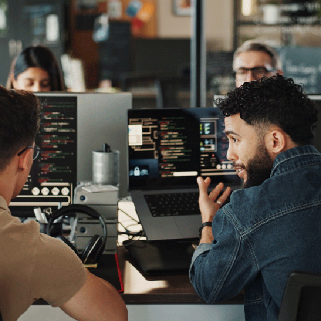 IT-Branche: Symbolbild. Zwei Männer im Gespräch vor PC-Monitoren. 640x640